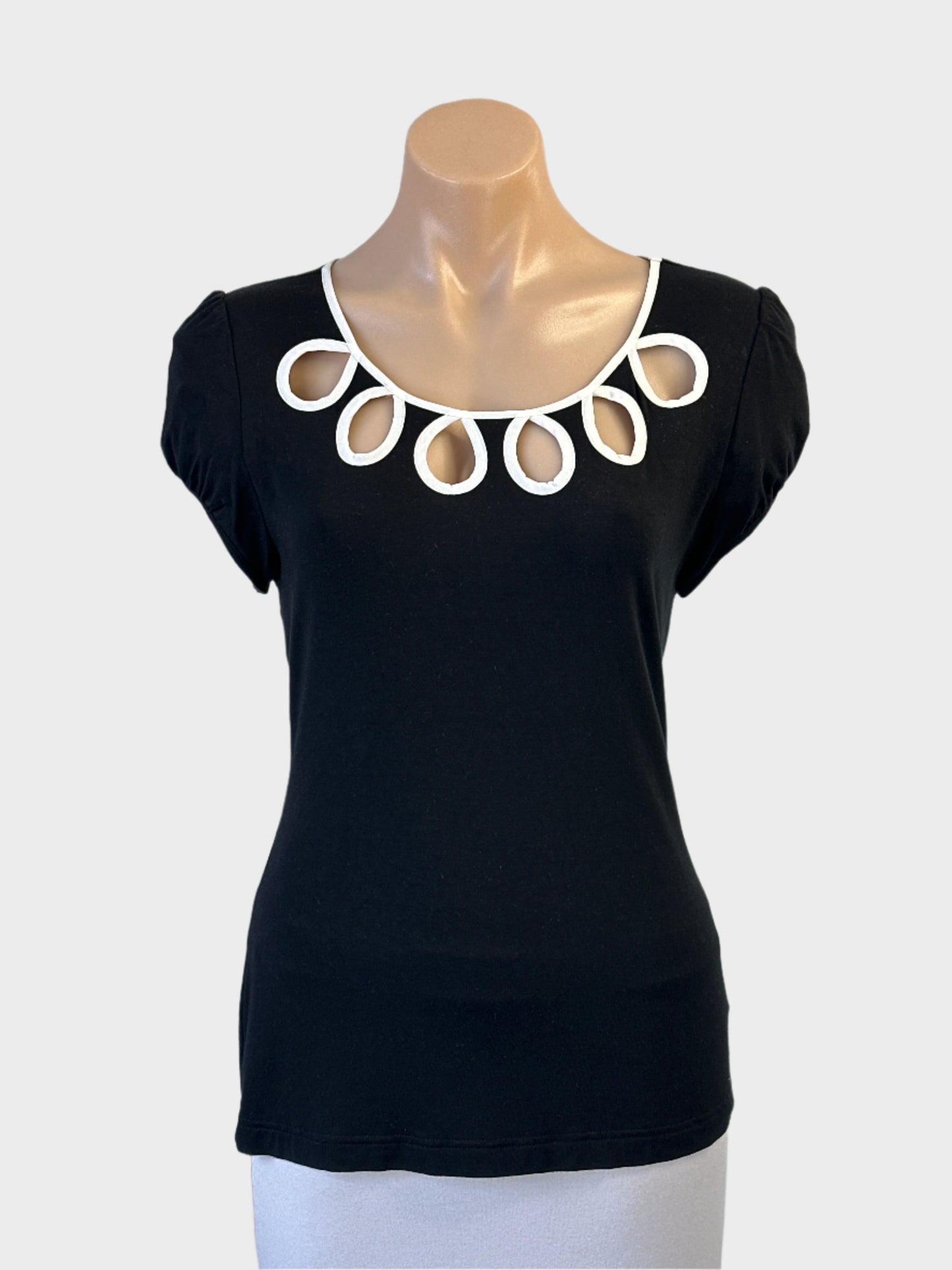 Review sleeveless top in black and white jersey with decorative eyelets for evening or office wear.