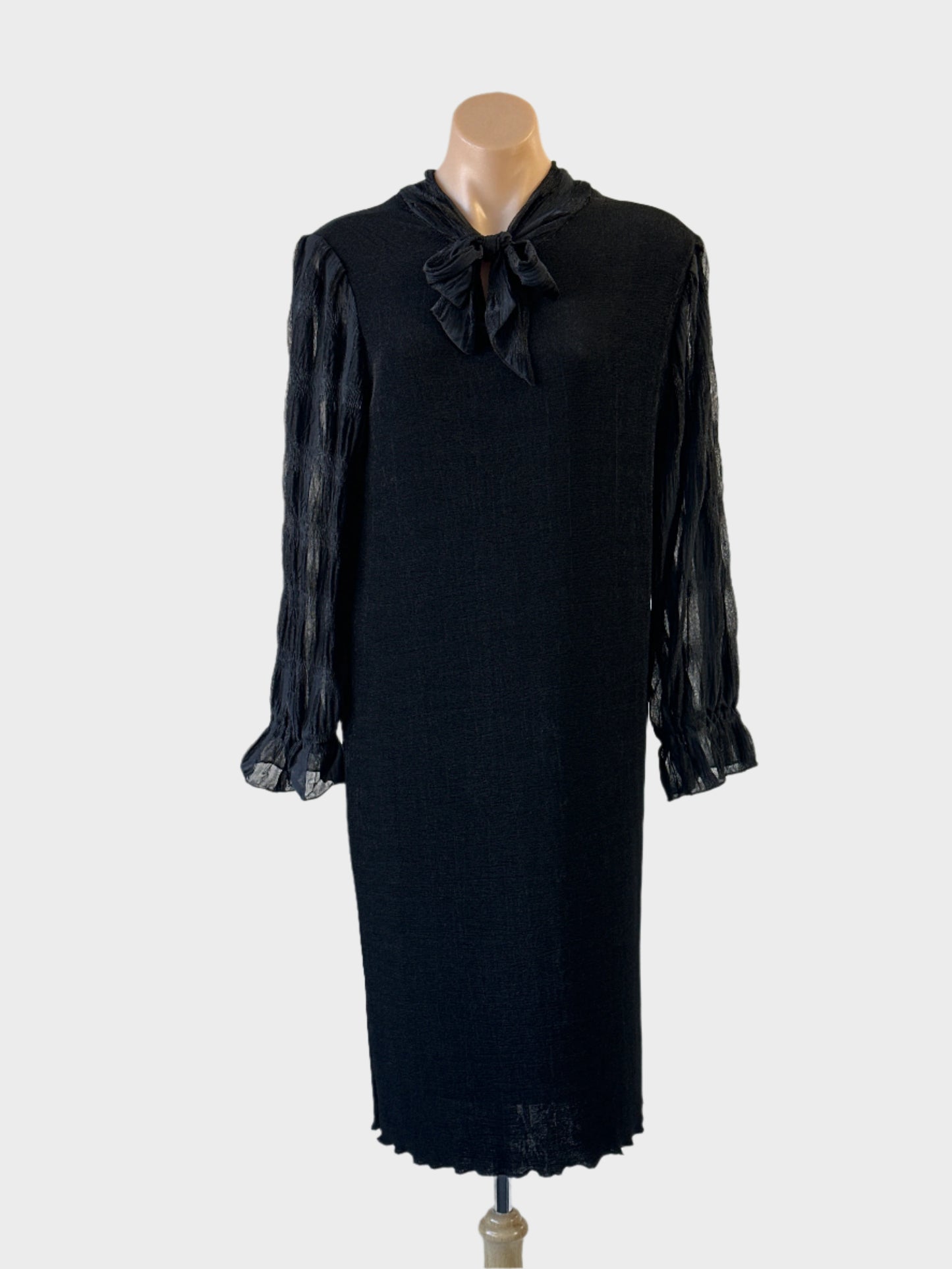 Shift dress in black knit with sheer sleeves and pussy bow neck for evening or formal wear.