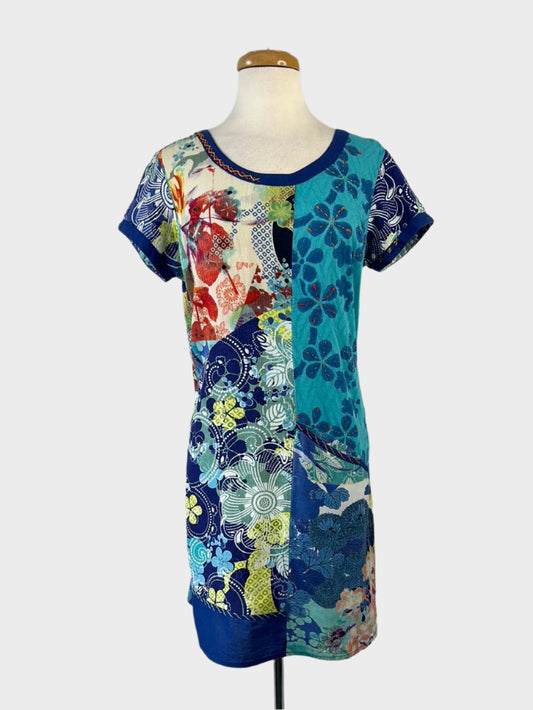 Orientique sleeveless shift dress in blue floral print with embroidery, scoop neck, cap sleeves, and skirt with in-seam pockets for resort wear.