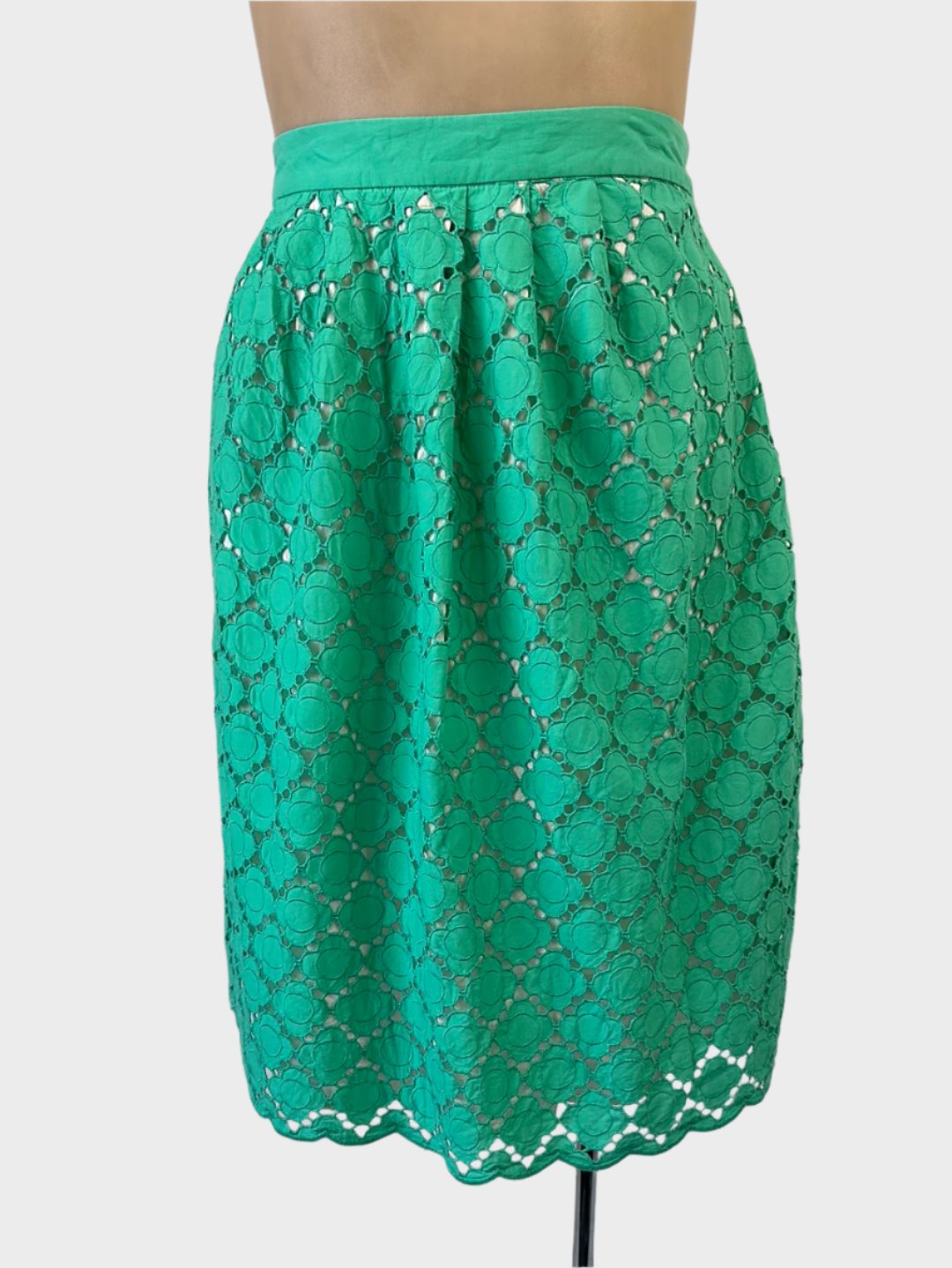 Boden pleated skirt in green guipure lace with daisy pattern, contrasting lining, waistband, and scalloped hem for office wear.