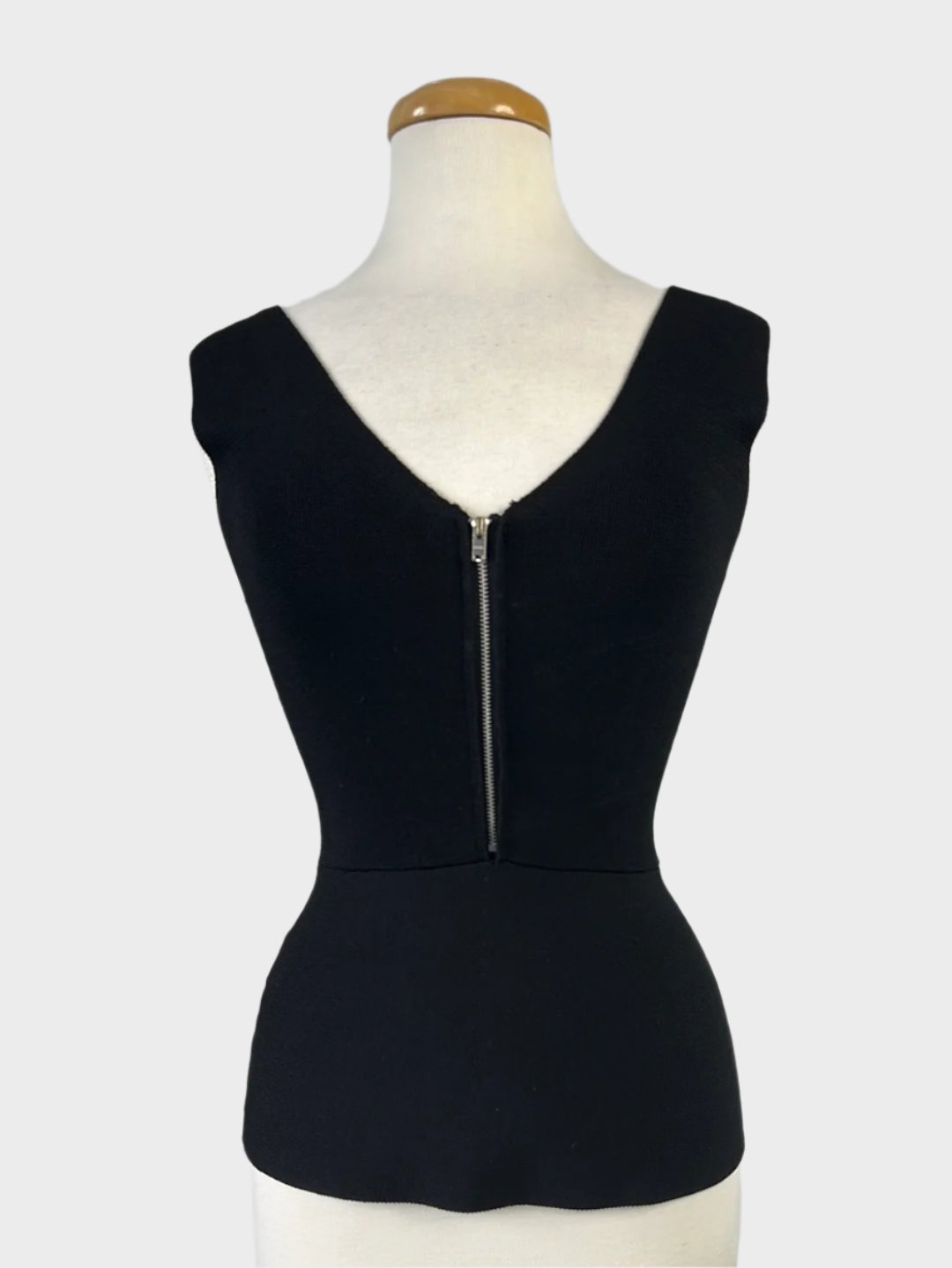 Portmans sleeveless peplum top in black rib knit with v-neck, v-shaped back, and zip front closure for evening wear.