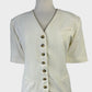 Vintage 80's cardigan jacket in cream with tortoise shell buttons, short sleeves, and front pockets for office wear.