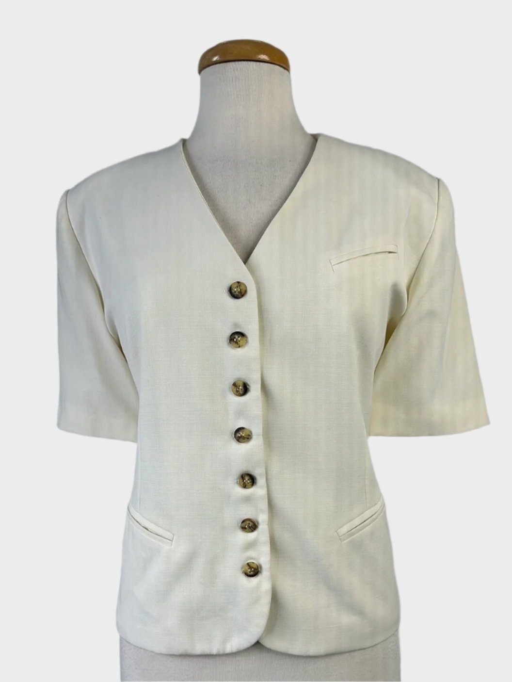 Vintage 80's cardigan jacket in cream with tortoise shell buttons, short sleeves, and front pockets for office wear.