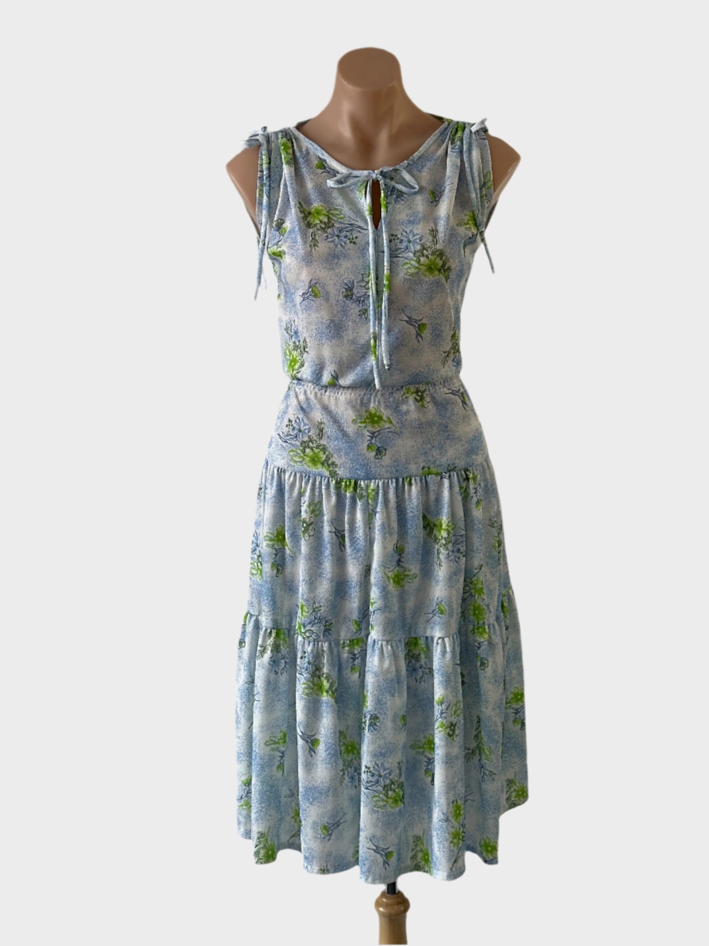 Vintage Fleur Jasmine sleeveless A-line dress in blue and white floral jersey, featuring keyhole neck, gathered shoulders, top stitched yoke waist, and tiered skirt for smart casual wear.