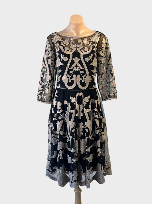 Black and beige sheer mesh A-line dress with floral appliqué, bateau neck and full skirt for evening or special events.