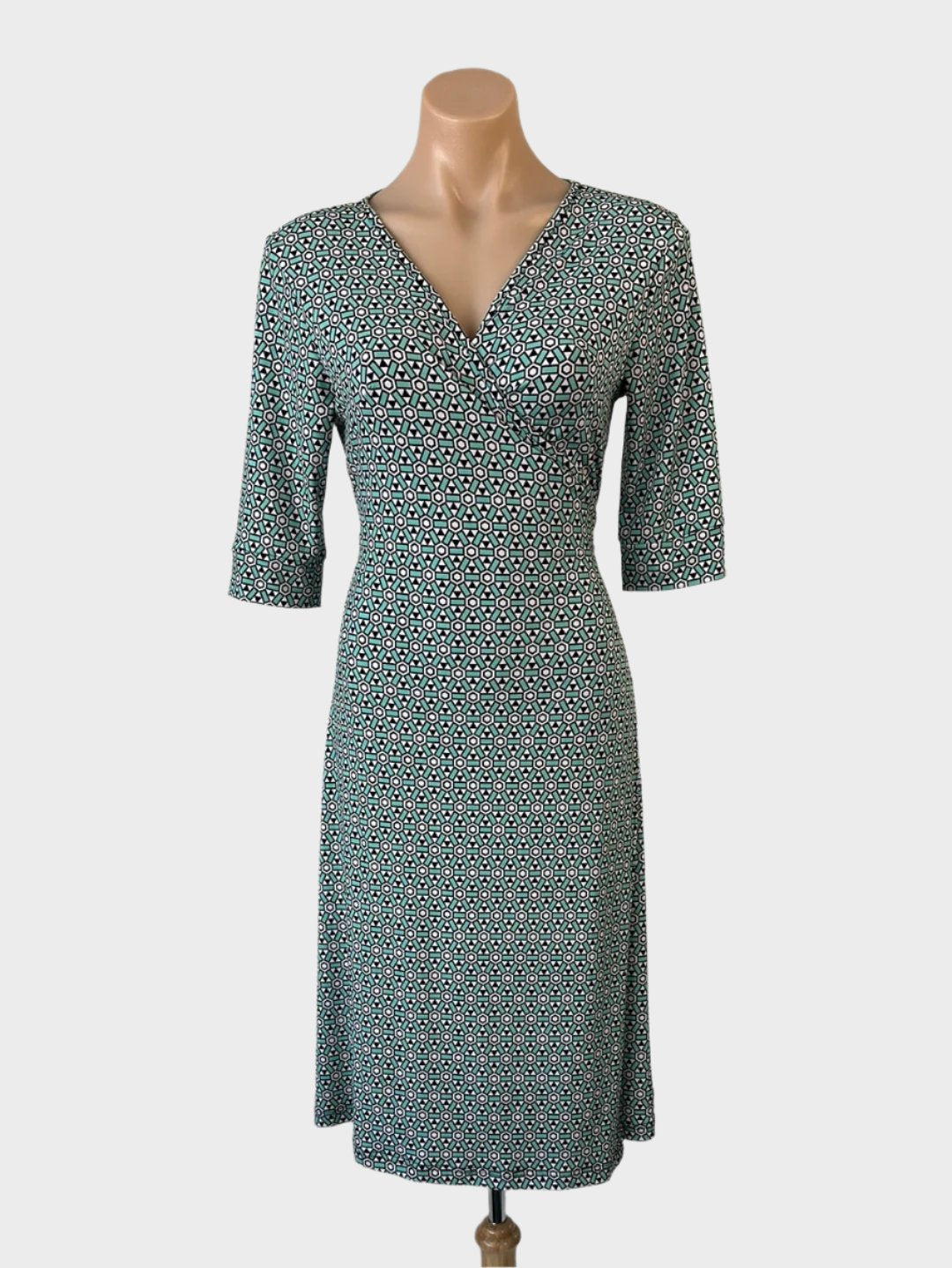 Diane von Furstenberg wrap dress in green silk jersey with geometric print, surplice neck, and straight skirt for office wear.