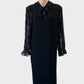 Shift dress in black knit with sheer sleeves and pussy bow neck for evening or formal wear.
