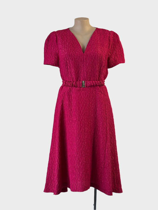 Veronika Maine pink A-line dress in puckered weave with high low hem and belt for special events.